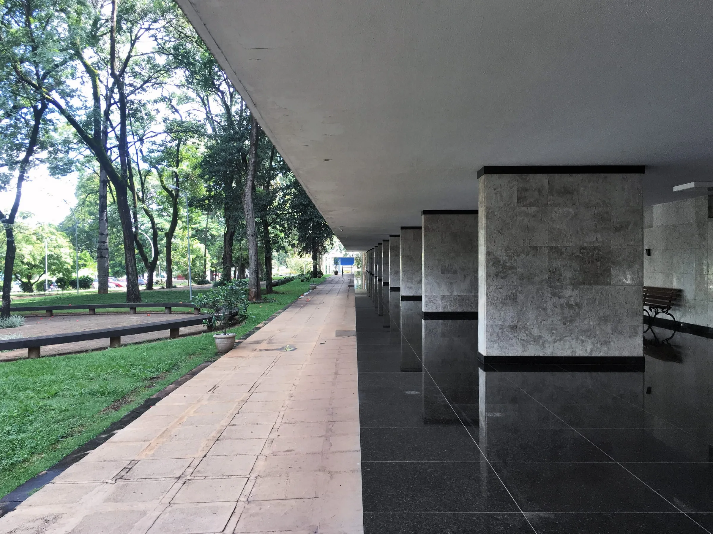Pilotis de um prédio de superquadra em Brasília: colunas de pedra, o piso livre e o gramado com árvores ao lado